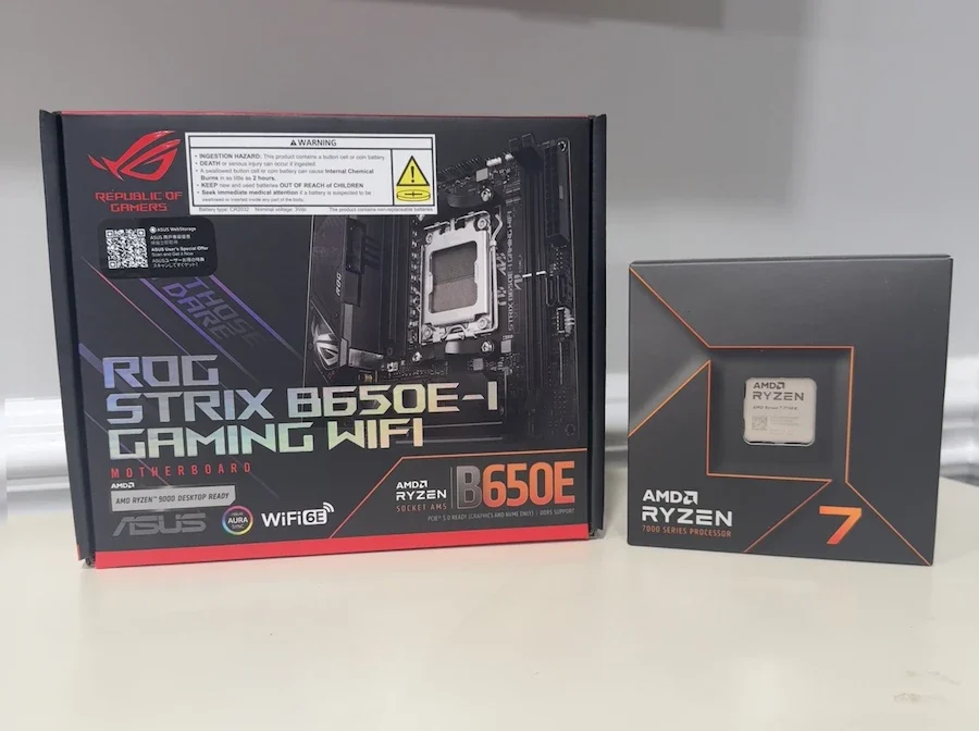 AMD Ryzen 7 7700X processor box next to ASUS ROG Strix B650E-I Gaming WiFi motherboard box